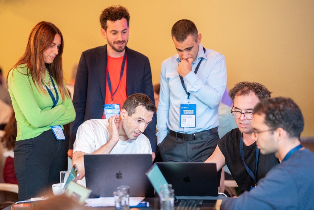 Gruppe von Konferenzteilnehmern diskutiert gemeinsam an Laptops um einen Tisch