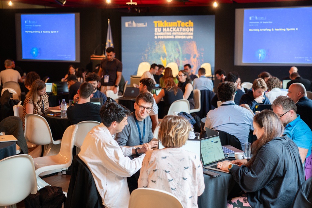 Teilnehmende arbeiten an Laptops und diskutieren bei einem Hackathon im Konferenzraum